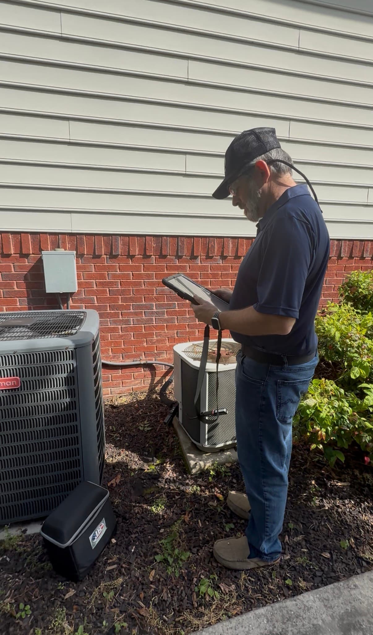 Russell taking diagnostic readings on an iPad at a customer's outdoor condenser unit